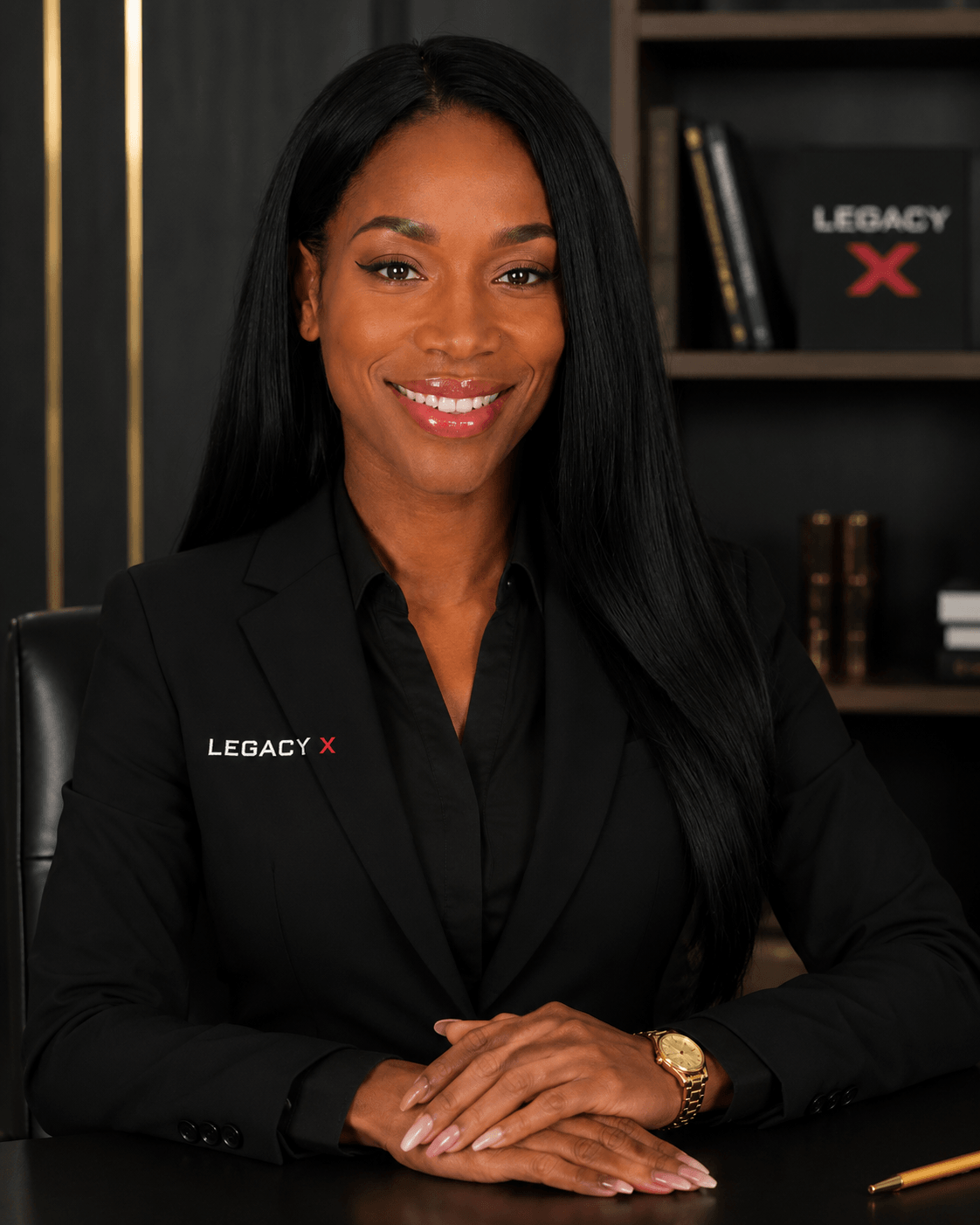 Jai Thompson, founder of Pretty Boi Legacy Group, in a black suit at his desk